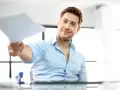Uśmiechnięty mężczyzna podaje dokumenty, które zawierają kluczowe dane do umowy o pracę.