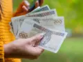Dłoń trzyma polskie banknoty 200 zł, które mogą stanowić ekwiwalent za urlop.