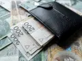 Czarny portfel na stosie polskich banknotów 200 zł. Wiele wskazuje na podwyżkę najniższej krajowej.