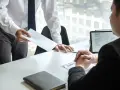 Pracodawca wręcza kopertę, a pracownik patrzy na dokumenty. Czy pracodawca może zmusić do urlopu?