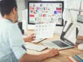 Mężczyzna, jako ux ui designer, analizuje wydruki z projektami na biurku.