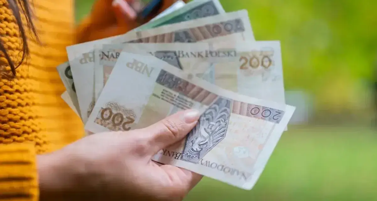 Dłoń trzyma polskie banknoty 200 zł, które mogą stanowić ekwiwalent za urlop.