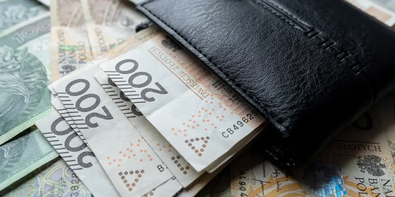 Czarny portfel na stosie polskich banknotów 200 zł. Wiele wskazuje na podwyżkę najniższej krajowej.