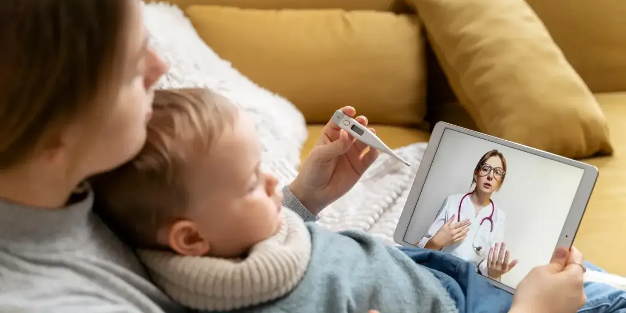 Mama mierzy temperaturę dziecku, konsultując się z lekarzem online. L4 na dziecko przez teleporadę.