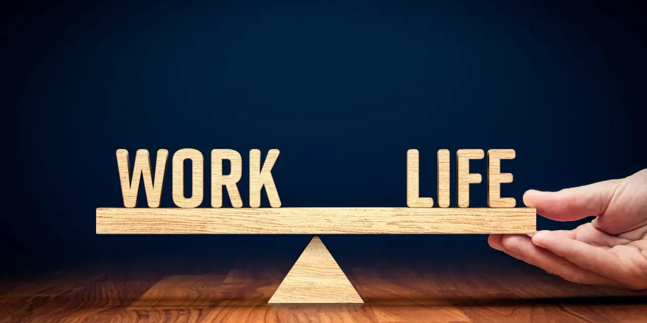 Waga symbolizująca work life balance co to jest. Drewniane litery "WORK" i "LIFE" na szali.