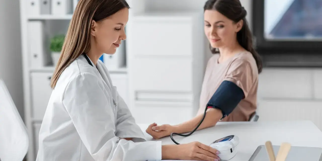 Lekarka mierzy ciśnienie pacjentce. Wynik l4 powyżej 30 dni wymaga dalszej diagnostyki.