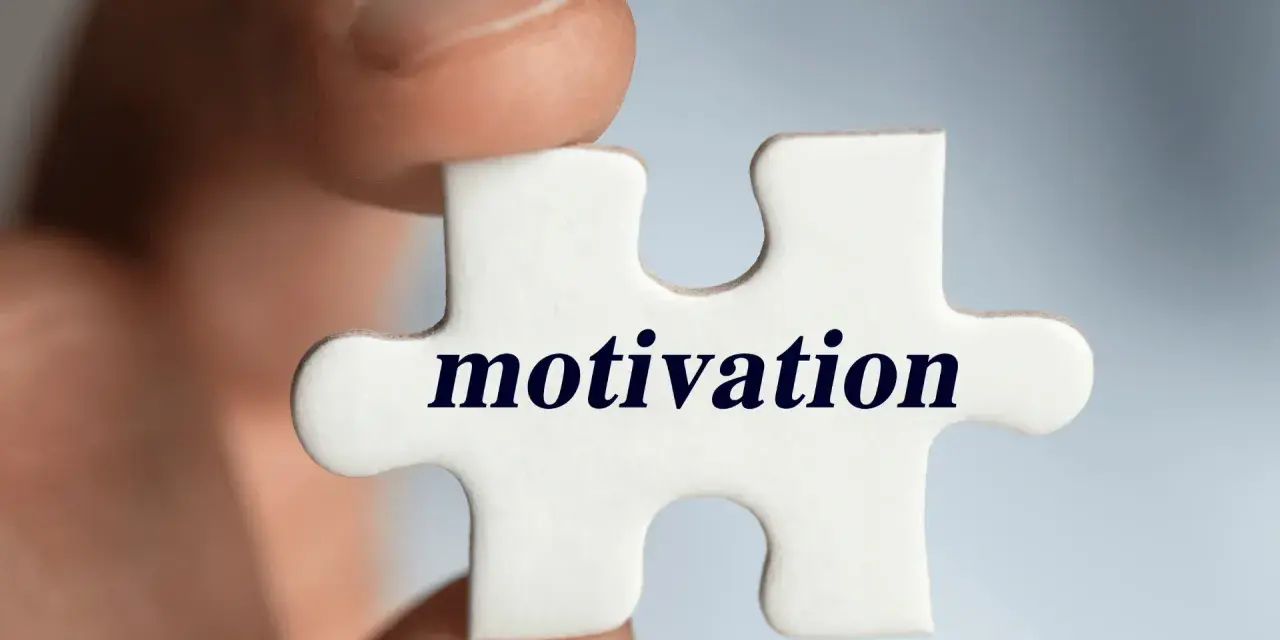 Palec trzyma element układanki z napisem "motivation". Klucz do sukcesu i tego, jak motywować pracowników, tkwi w znalezieniu właściwego elementu.