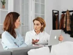 Kobiety omawiają wynagrodzenie za urlop, analizując dane na laptopie.
