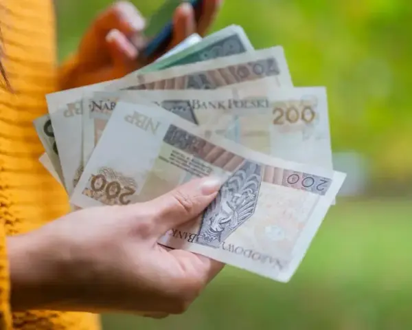 Dłoń trzyma polskie banknoty 200 zł, które mogą stanowić ekwiwalent za urlop.