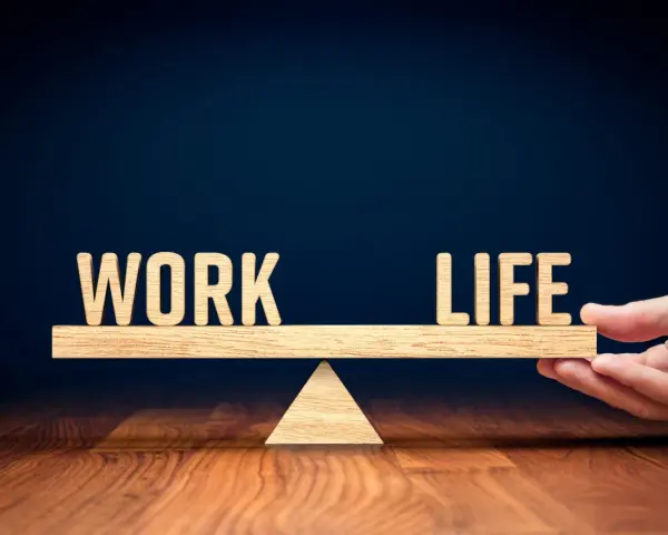 Waga symbolizująca work life balance co to jest. Drewniane litery "WORK" i "LIFE" na szali.