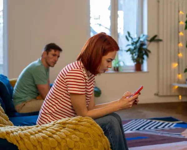 Kobieta zapatrzona w telefon, ignoruje partnera. Czy to początek problemów, jak rozmawiać z toksykiem?
