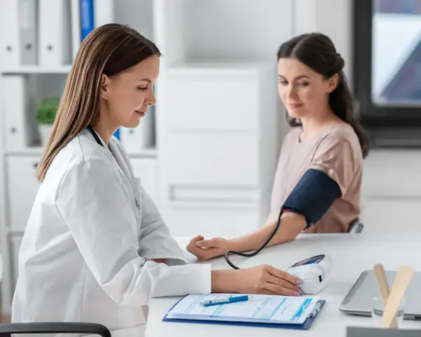Lekarka mierzy ciśnienie pacjentce. Wynik l4 powyżej 30 dni wymaga dalszej diagnostyki.