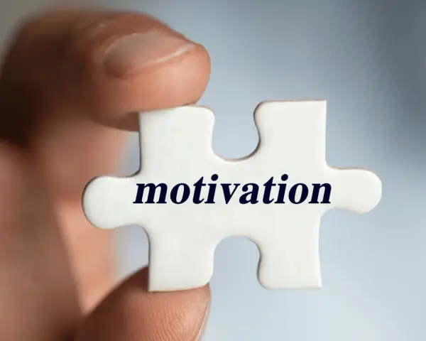 Palec trzyma element układanki z napisem "motivation". Klucz do sukcesu i tego, jak motywować pracowników, tkwi w znalezieniu właściwego elementu.