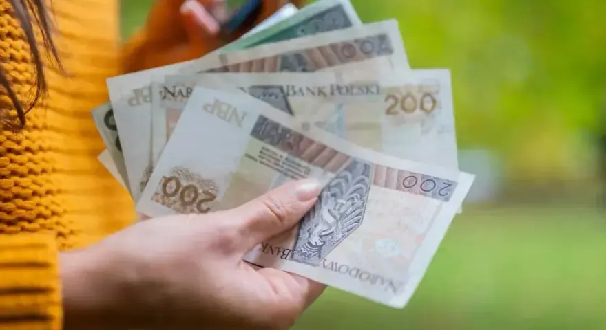 Dłoń trzyma polskie banknoty 200 zł, które mogą stanowić ekwiwalent za urlop.