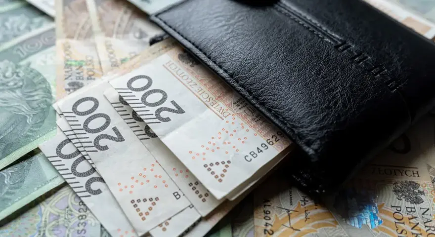 Czarny portfel na stosie polskich banknotów 200 zł. Wiele wskazuje na podwyżkę najniższej krajowej.