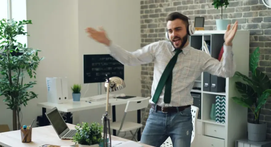 Szczęśliwy ENFP w pracy, tańczący w słuchawkach. W tle biuro z roślinami i komputerami.