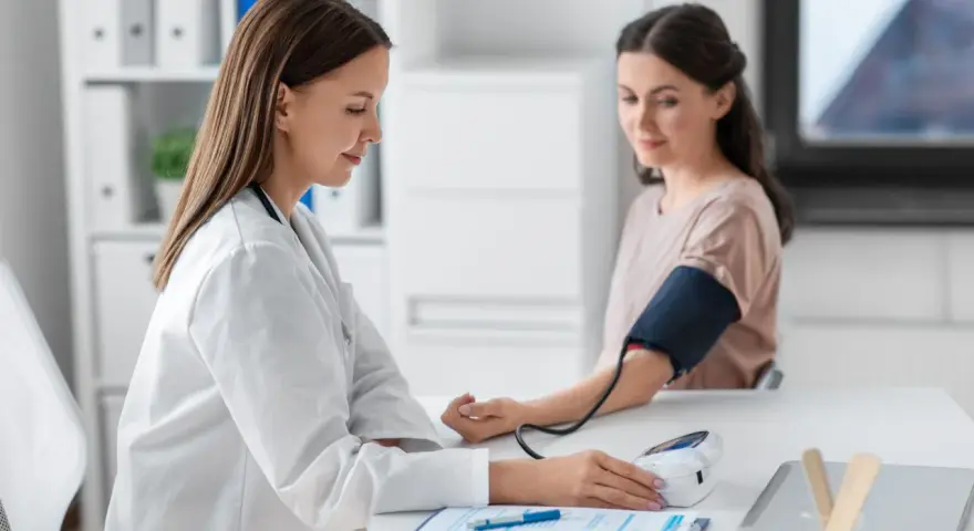 Lekarka mierzy ciśnienie pacjentce. Wynik l4 powyżej 30 dni wymaga dalszej diagnostyki.