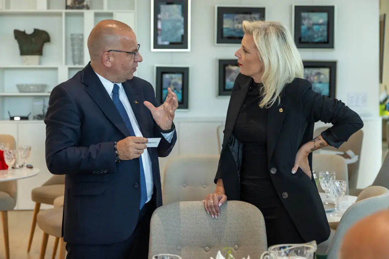 Mężczyzna w garniturze tłumaczy kobiecie, jak zacząć networking. Rozmowa biznesowa w eleganckim wnętrzu.