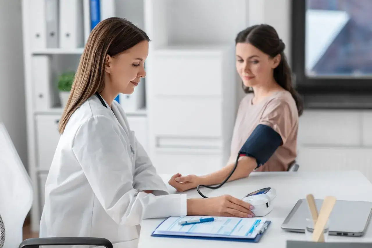 Lekarka mierzy ciśnienie pacjentce. Wynik l4 powyżej 30 dni wymaga dalszej diagnostyki.