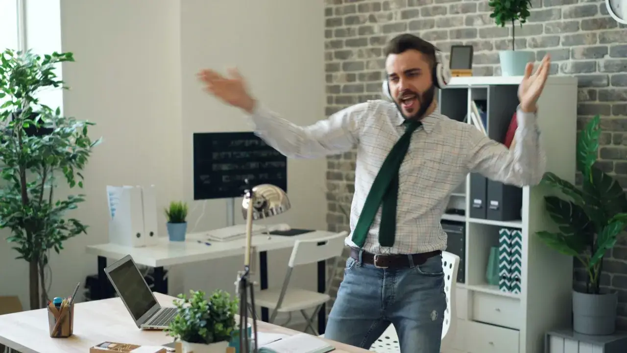 Szczęśliwy ENFP w biurze, tańczący w słuchawkach. Widać jego entuzjazm i kreatywność, idealne do zawod&oacute;w wymagających innowacji.