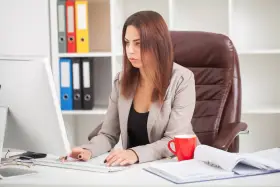 Kobieta w biurze pracuje przy komputerze, zastanawiając się, czy staż z urzędu pracy wlicza się do stażu pracy.